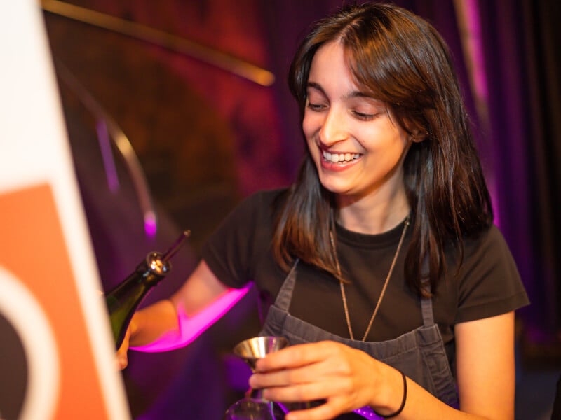 woman smiling as she makes cocktails
